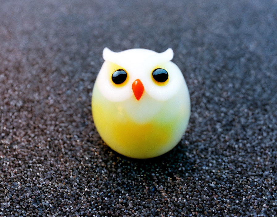 Small Yellow and White Owl Figurine on Gritty Surface