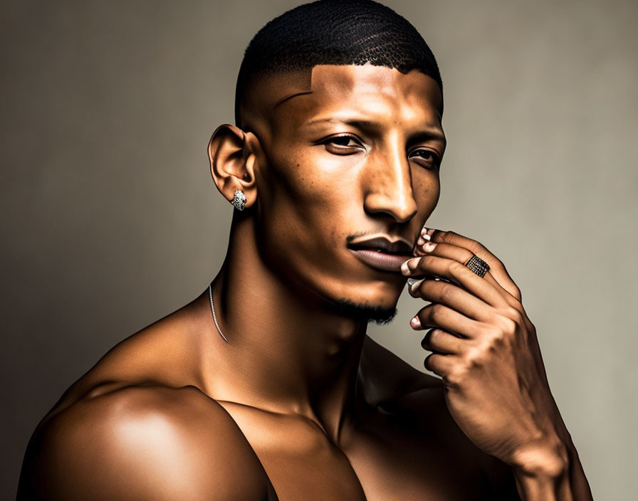 Pensive shirtless man with goatee and earring on neutral background