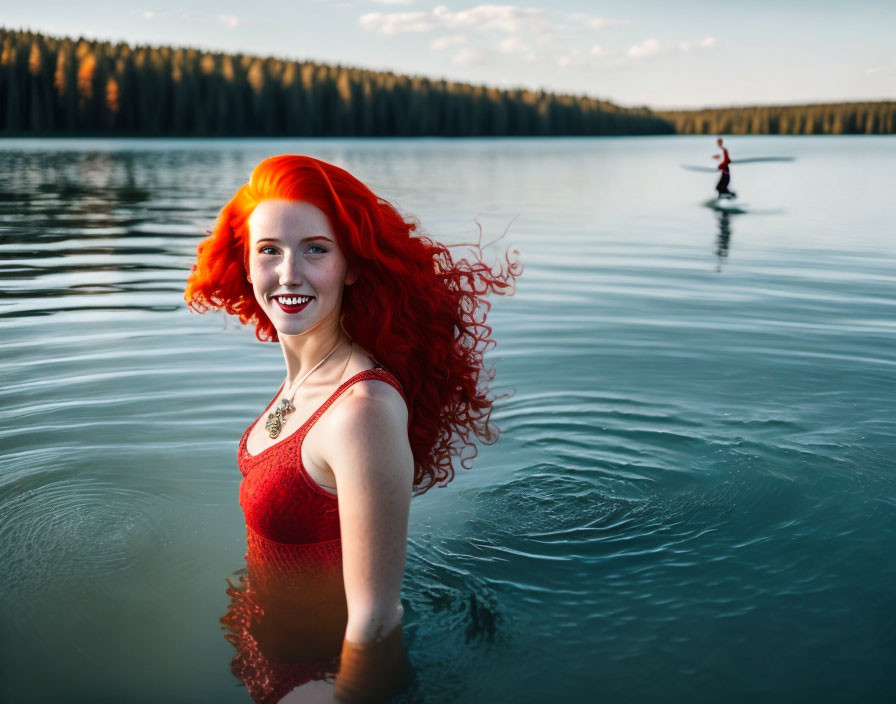 Vibrant red-haired woman in red swimsuit at lake with paddleboarder