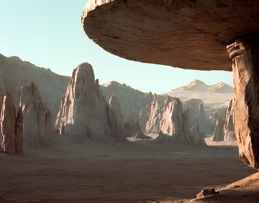 Desert landscape with towering rock formations and overhanging plateau.