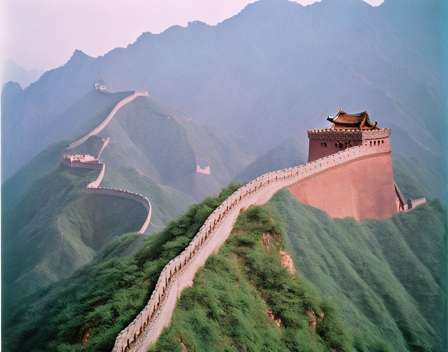 Majestic Great Wall of China in lush green hills with watchtower under hazy sky