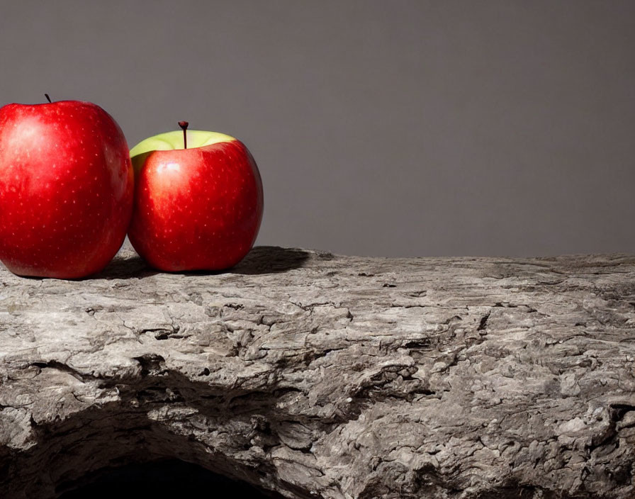 Red and green apples on textured wooden surface.