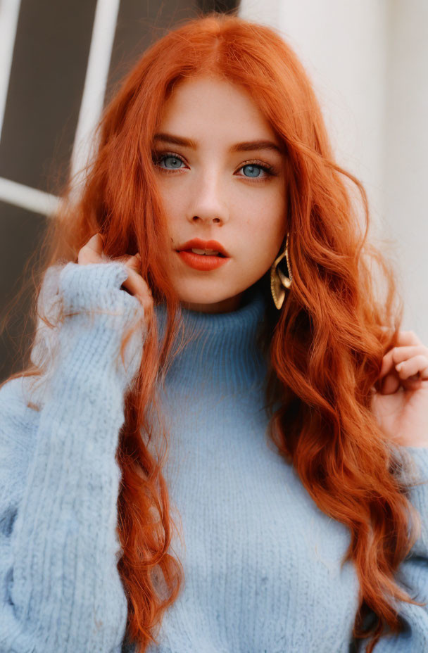 Woman with Red Hair and Blue Eyes in Blue Sweater and Gold Earrings Portrait