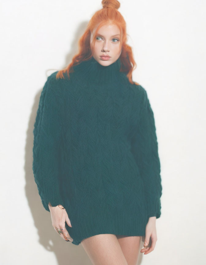 Red-haired person in teal turtleneck sweater against light backdrop