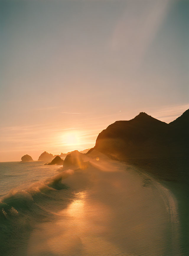 Tranquil beach scene at sunset with gentle waves and rock formations