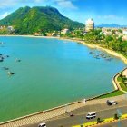 Vibrant coastal town scene with colorful buildings, beach, boats, and hills