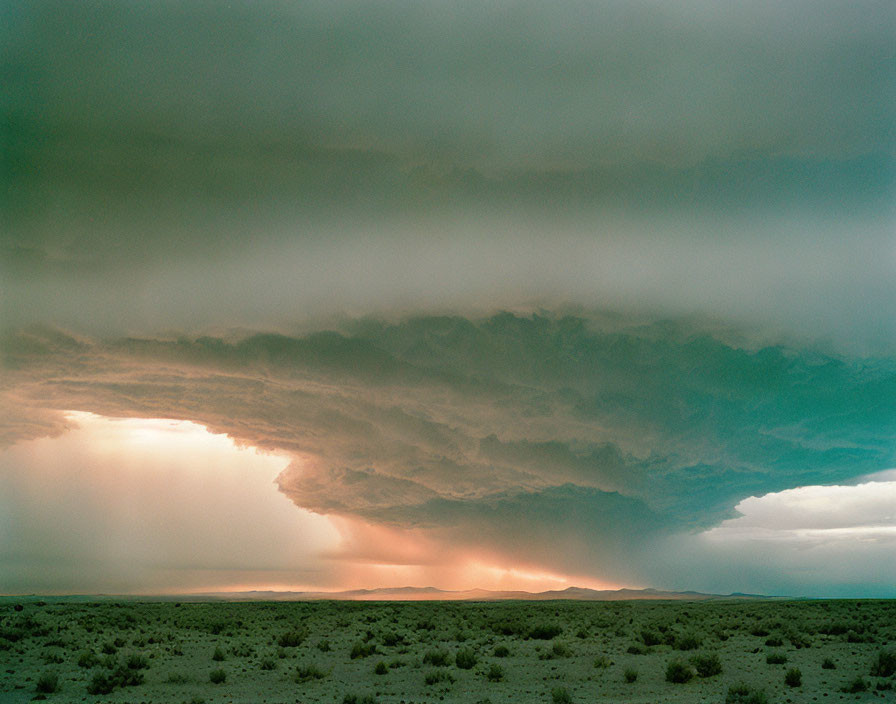 Dramatic desert landscape with orange sunset glow and stormy skies