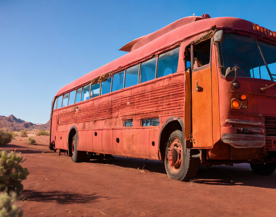 Abandoned red bus in desert landscape with clear skies