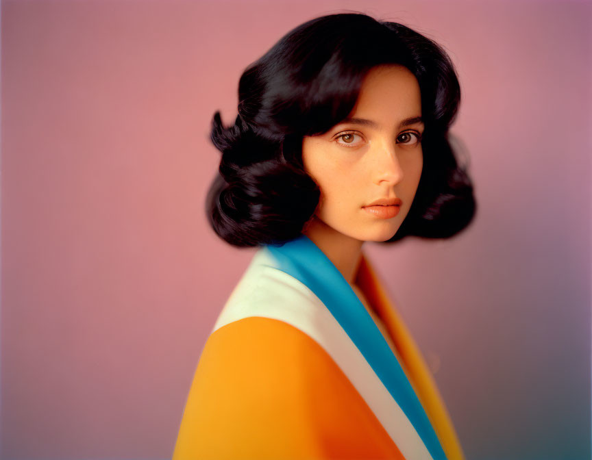 Woman with Shoulder-Length Dark Hair in Multicolored Top on Pink Background