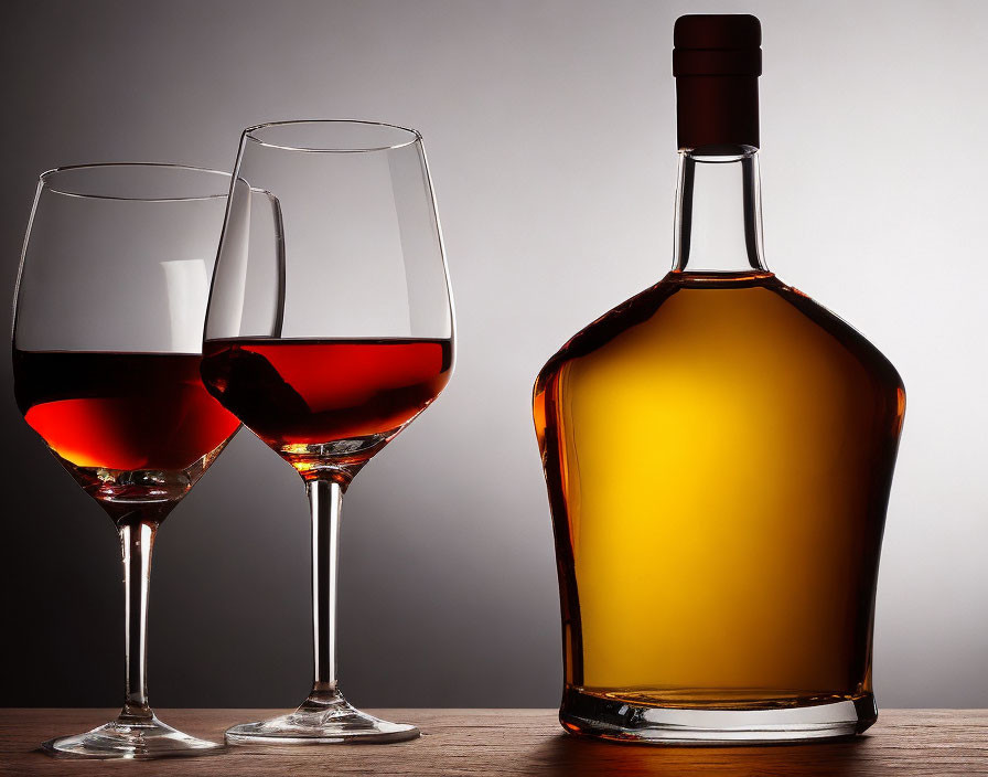 Red wine glasses and unopened bottle on neutral background