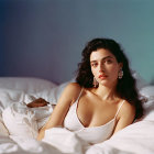 Woman in White Dress on Bed with Large Earrings in Dimly Lit Room