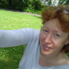 Woman with striking eyes and horse in bridle in greenery with white fence