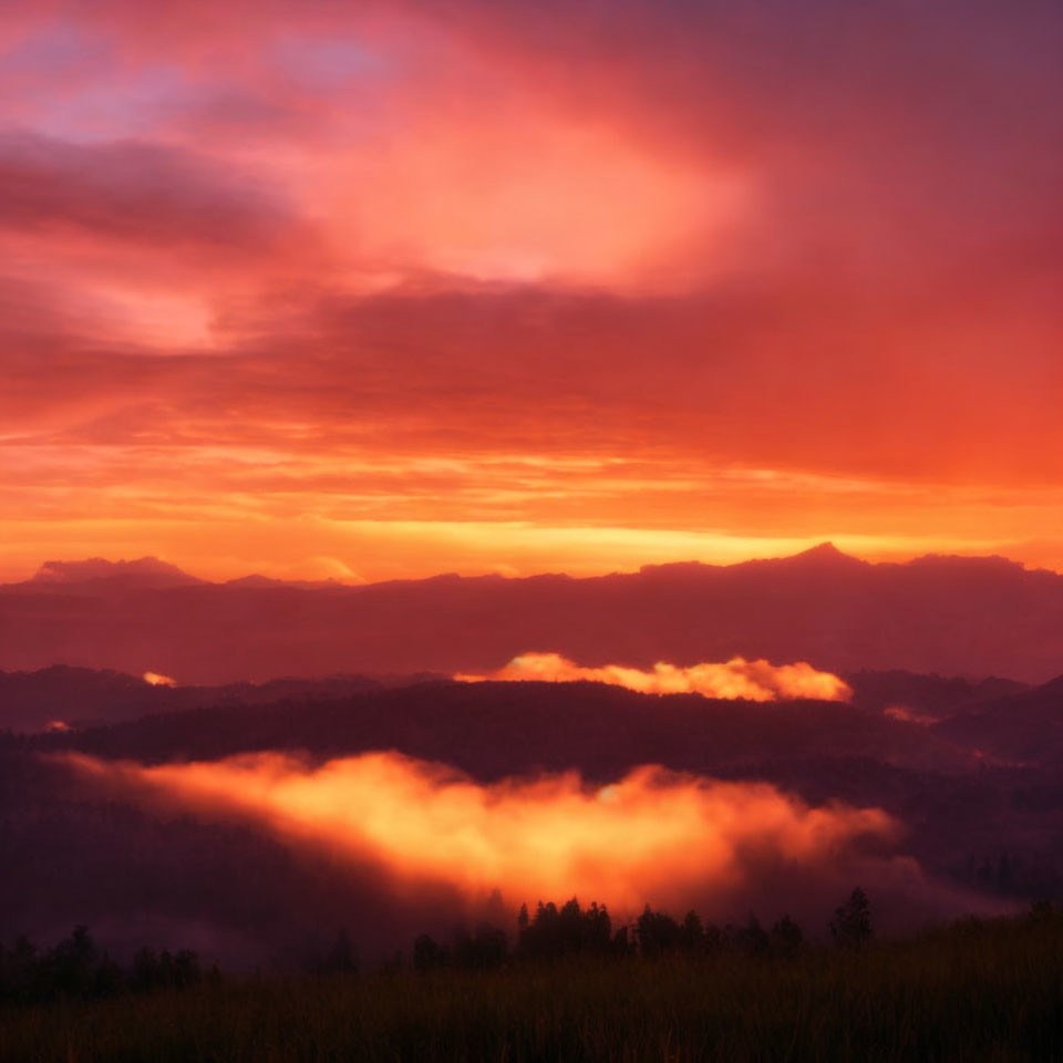 Vibrant sunrise over layered mountains with clouds and fiery sky