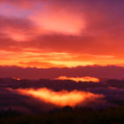 Vibrant sunrise over layered mountains with clouds and fiery sky