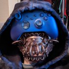 Skull mask with glowing blue eyes and mechanical details on hooded figure