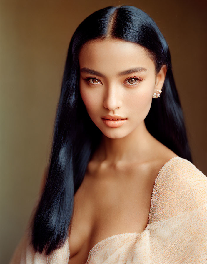 Portrait of woman with long black hair, fair skin, brown eyes, peach off-shoulder top