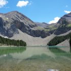 Tranquil lake reflecting colorful mountains and forest under blue sky