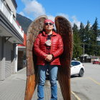 Warrior with Large Red Wings in Metallic Armor with Sword in Forested Area