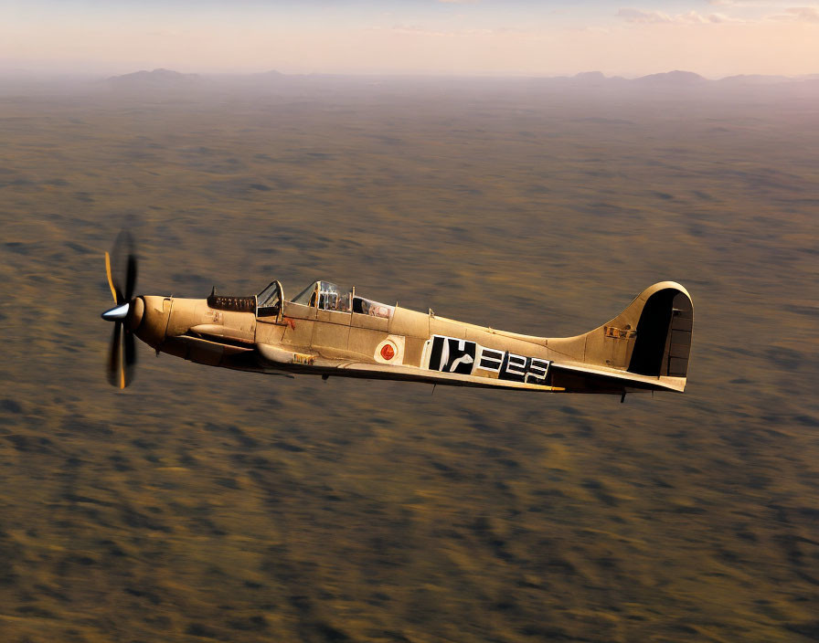 Vintage fighter plane flying low over rugged terrain with rolling hills and sparse vegetation under warm-hued sky.