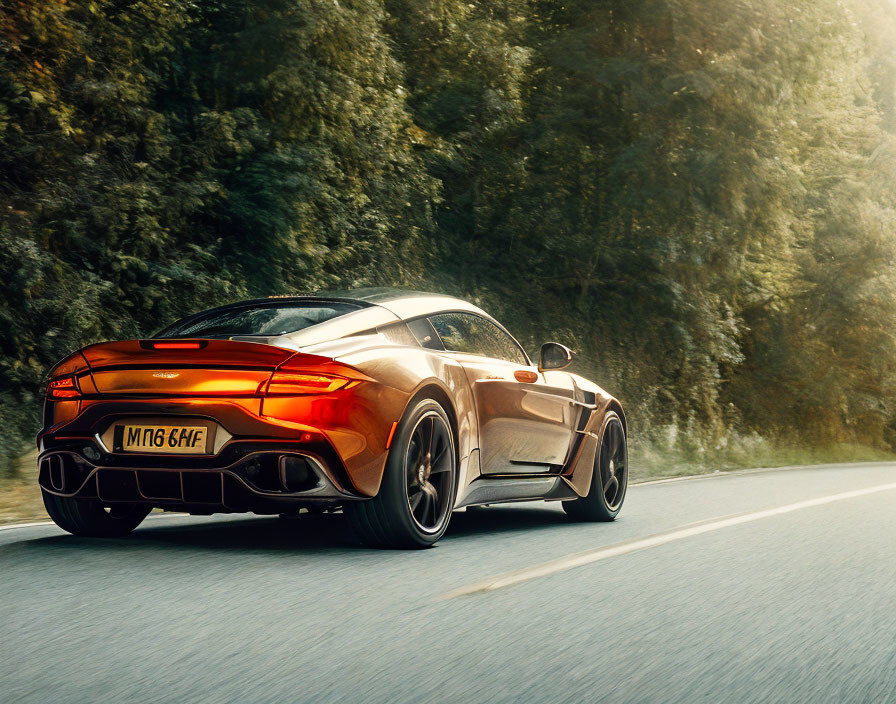 Orange Sports Car Driving on Tree-Lined Road