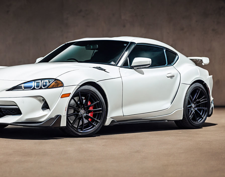 White Sports Car with Black Rims and Red Brake Calipers in Studio Setting