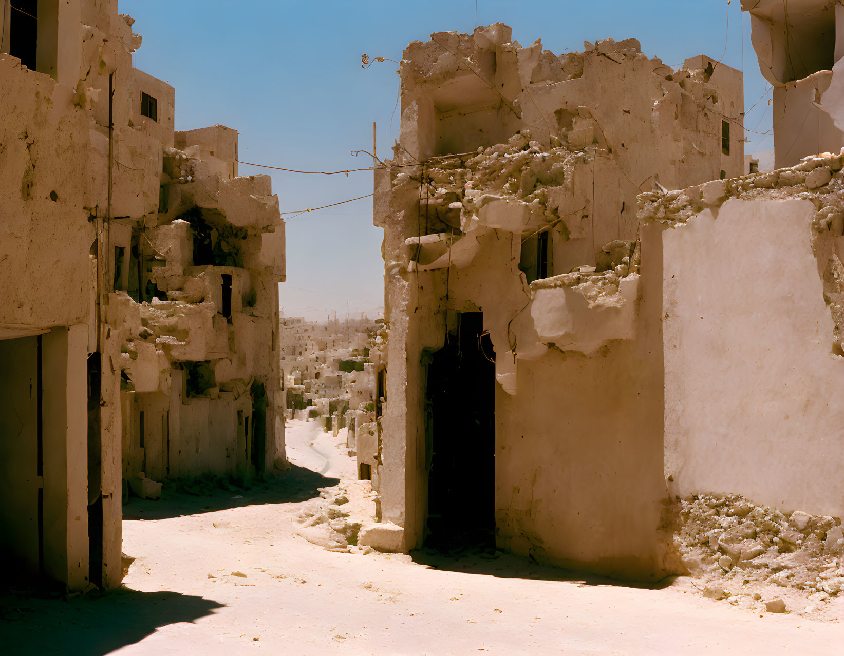 Destroyed city street after war with damaged buildings and rubble under clear sky