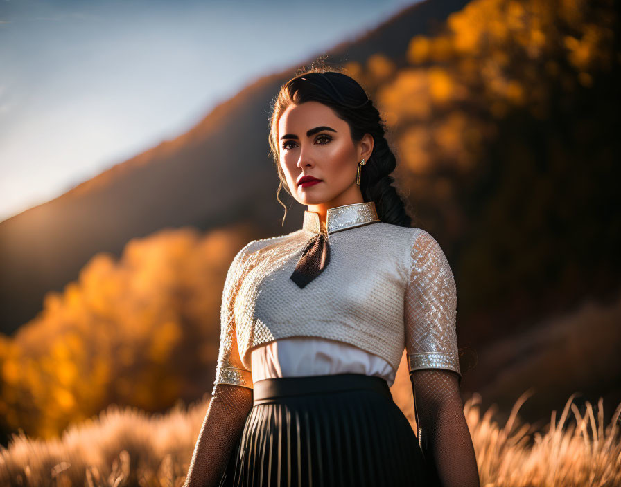 Woman in high-collar shirt and skirt posing in field with autumn trees