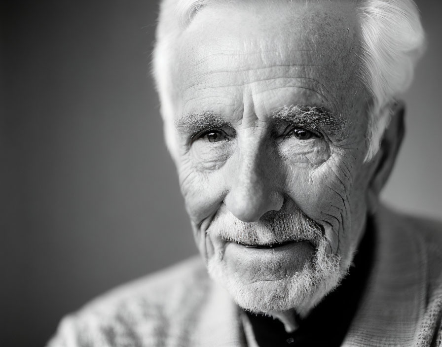 Portrait of elderly gentleman with white hair and gentle smile in monochrome.