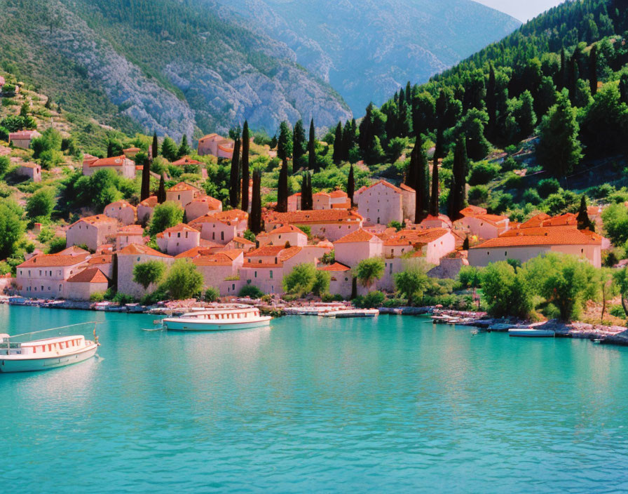 Coastal village with terracotta roofs, lush hills, turquoise water, and docked boats