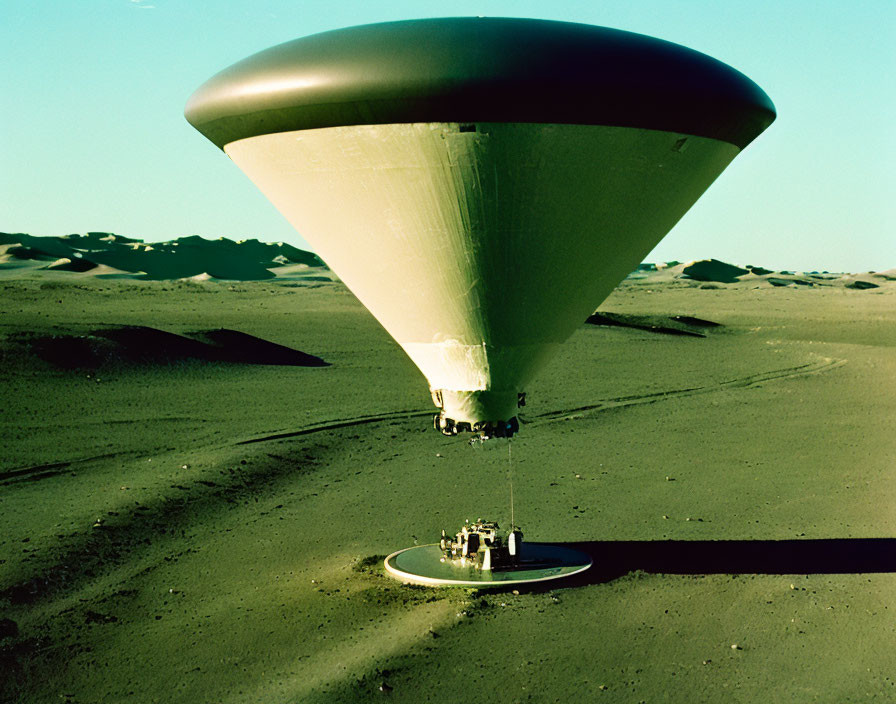 Airship casting shadow in desert landscape with attached equipment