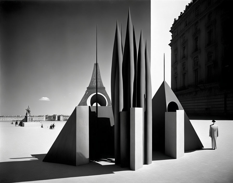 Monochrome image of person viewing abstract sculptures in outdoor plaza