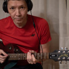 Musician in Red Shirt Playing Acoustic Guitar and Singing into Microphone