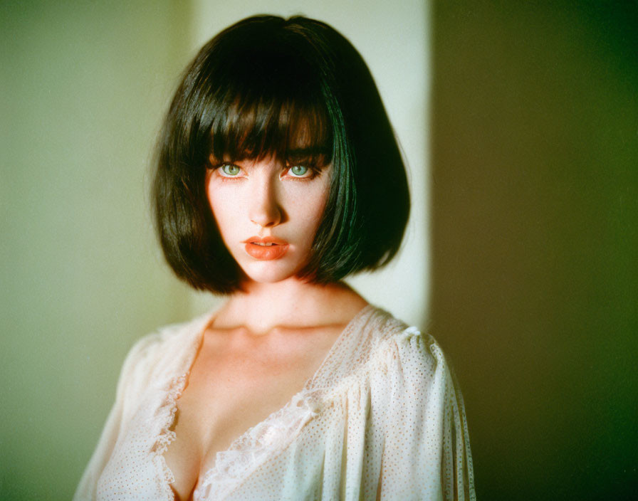 Blue-eyed woman with black bob in white lace top