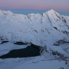 Tranquil landscape: serene lake, blooming shrubs, snow-capped mountains