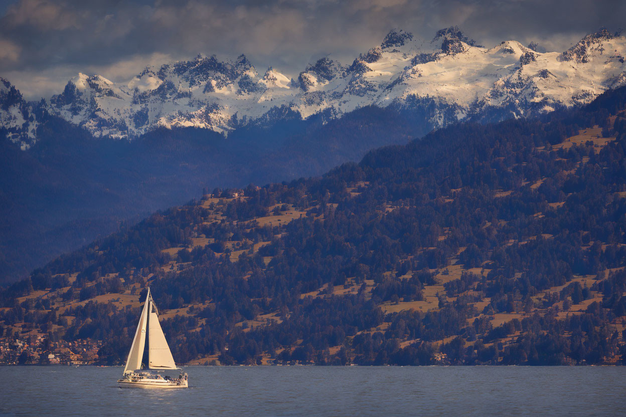 Sailboat on Calm Lake with Snow-Capped Mountains