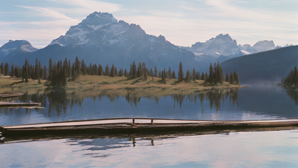 Tranquil lake scene with wooden pier, pine trees, and snow-capped mountains