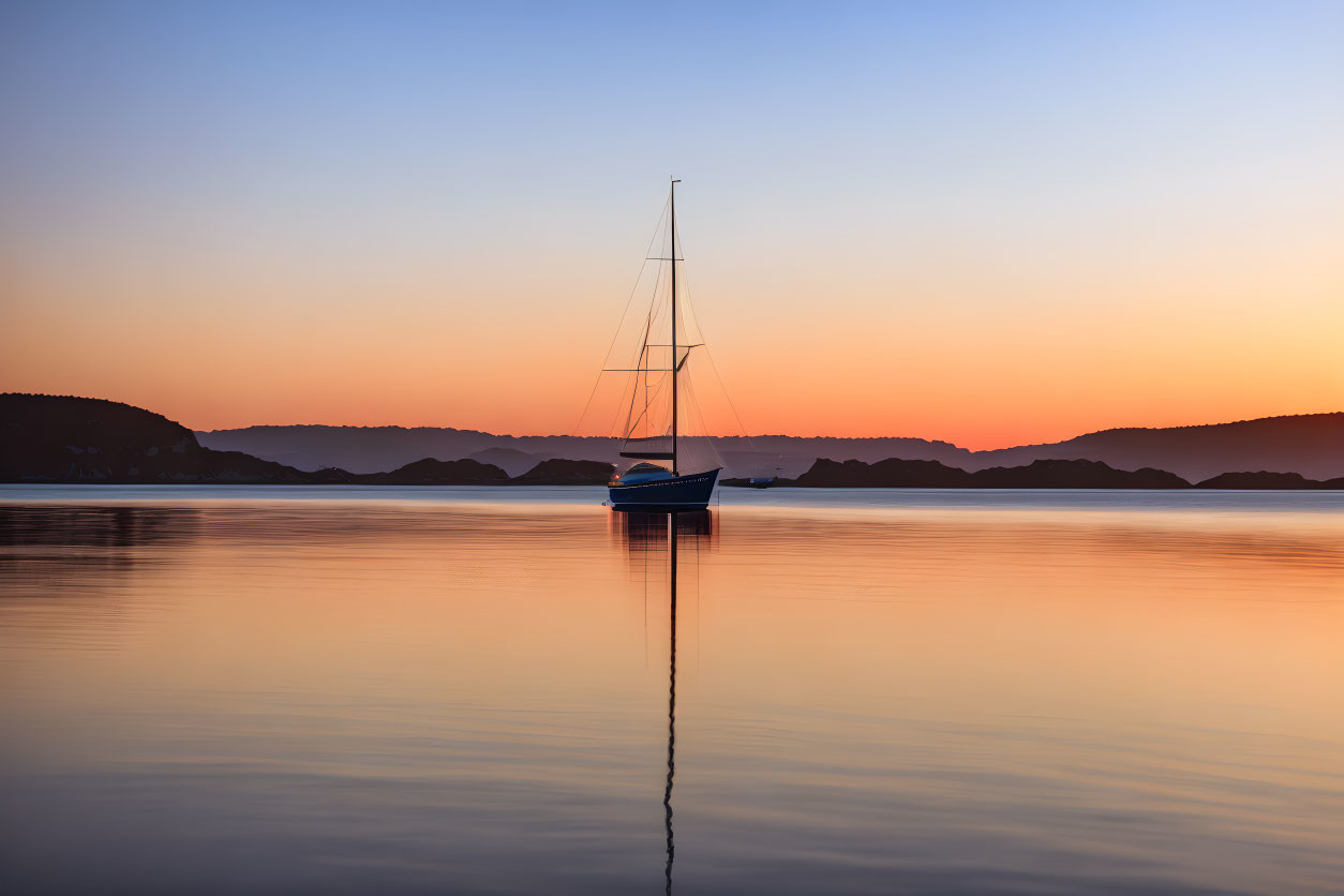 Tranquil sunset scene with sailboat on calm water