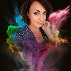 Short-haired woman surrounded by vibrant colored dust on dark background