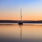 Tranquil sunset scene with sailboat on calm water