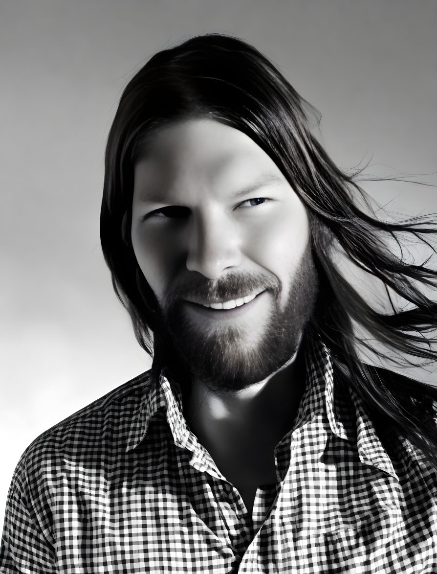 Smiling man with long hair and beard in monochrome portrait