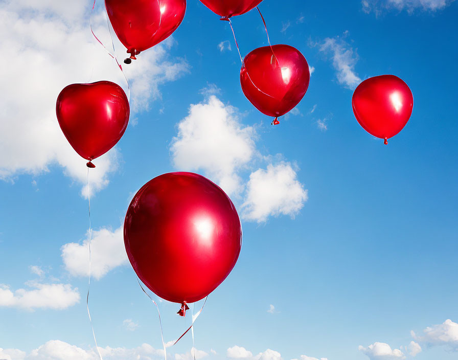 Red balloons against blue sky with white clouds