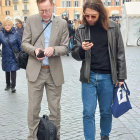 Two men in stylish attire on smartphones in city street with classical architecture