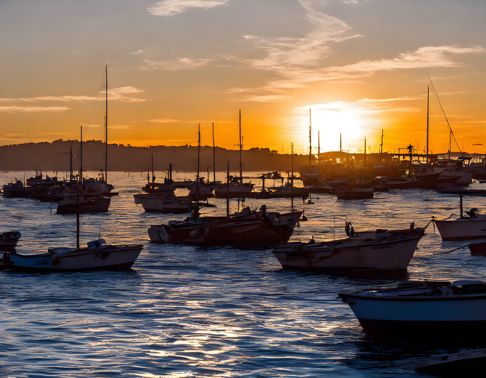 Harbor sunset with silhouetted boats on shimmering water