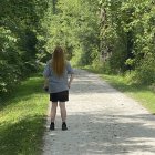 Person in Blue Coat Walking Through Lush Forest Path