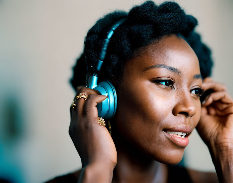 Smiling woman adjusting headphones with styled hair and golden ring