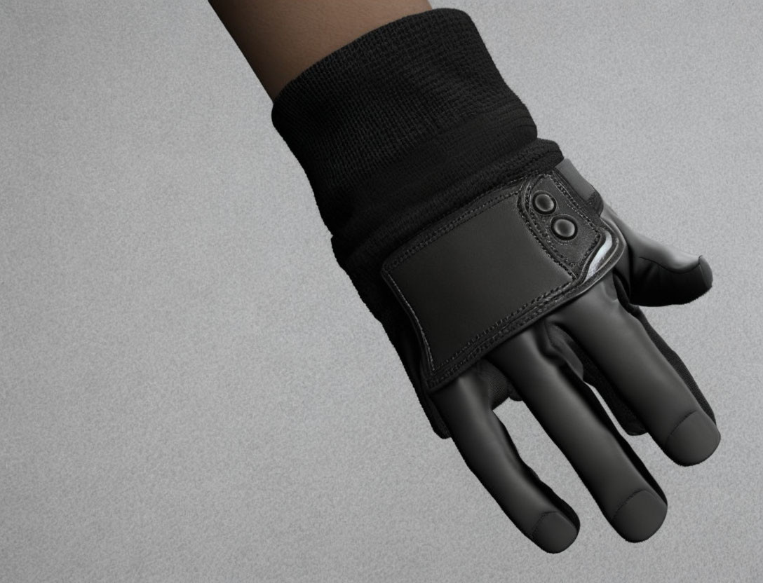 Black leather glove with snap fastener on hand against grey background