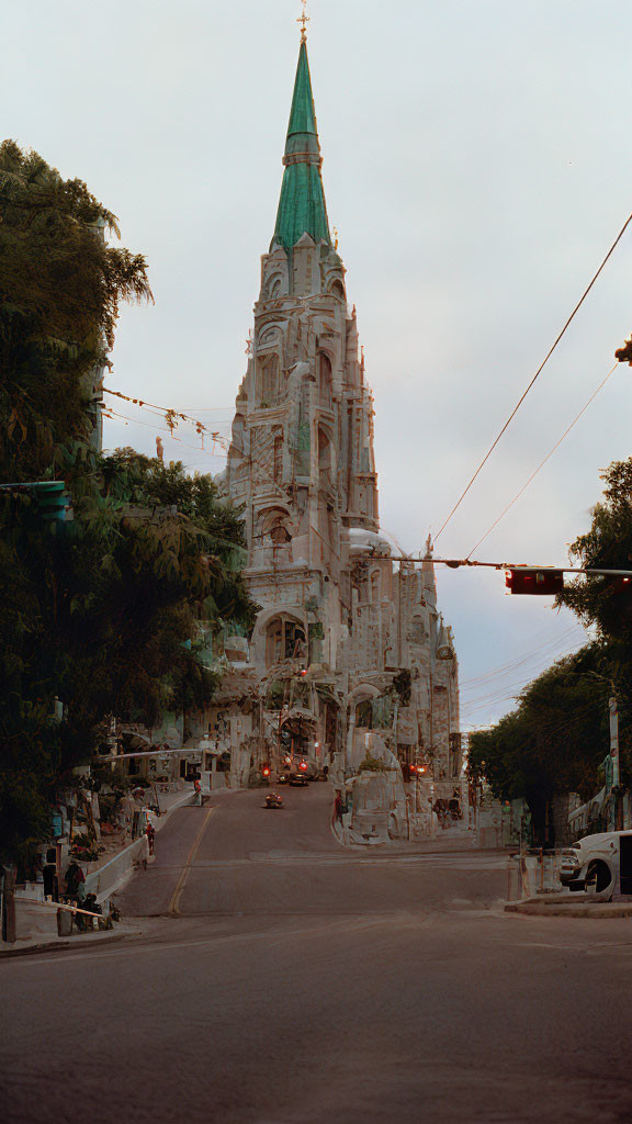 Green-spired church at dusk on street with parked cars