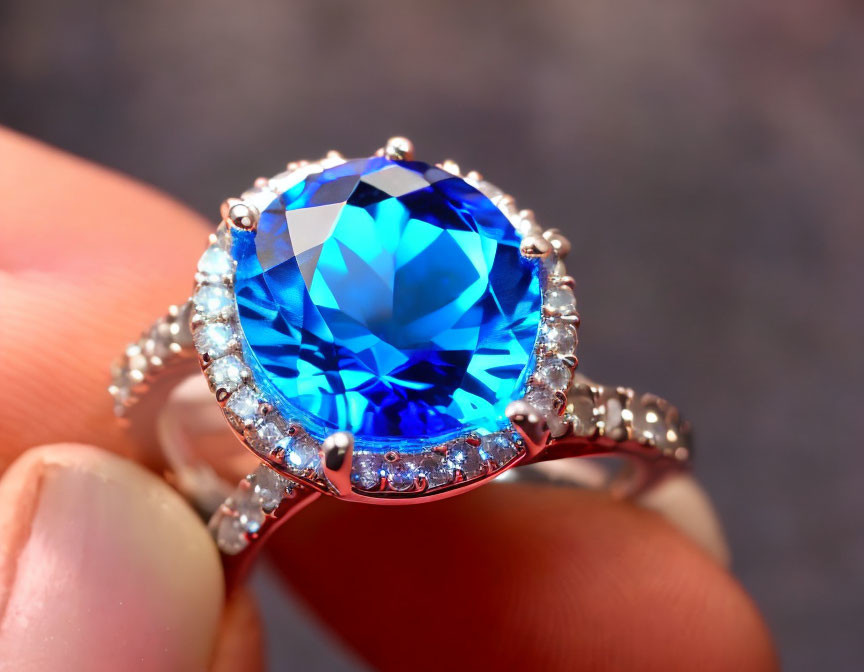 Close-up of hand holding blue gemstone ring with diamonds on silver band