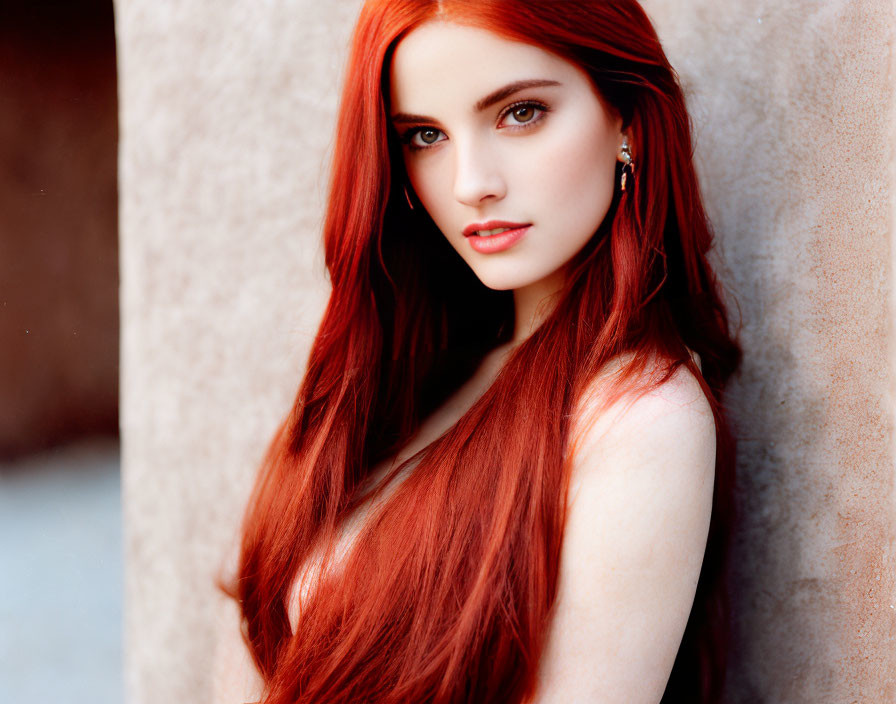 Woman with Long Red Hair and Fair Skin Leaning Against Tan Wall