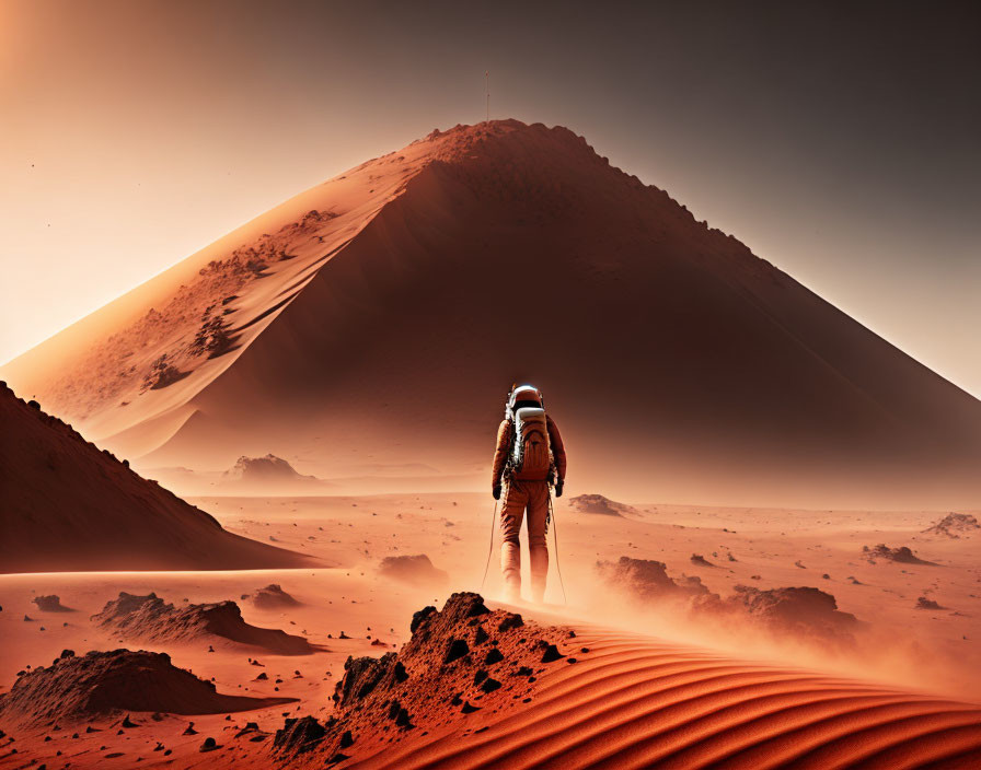 Astronaut in Mars-like landscape with large dune and hazy orange sky